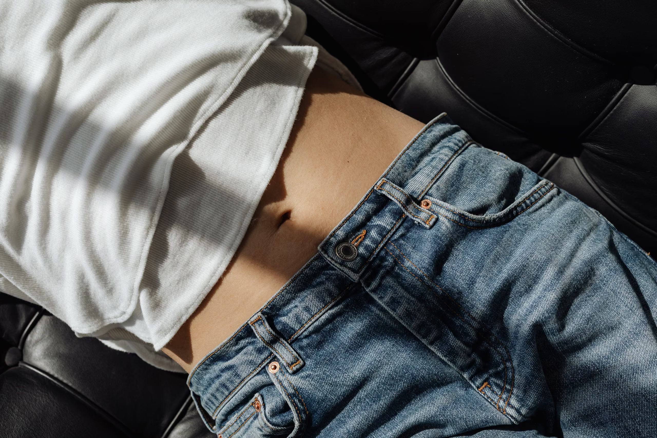 Le milieu du corps d'un femme habillée, allongée sur un canapé
